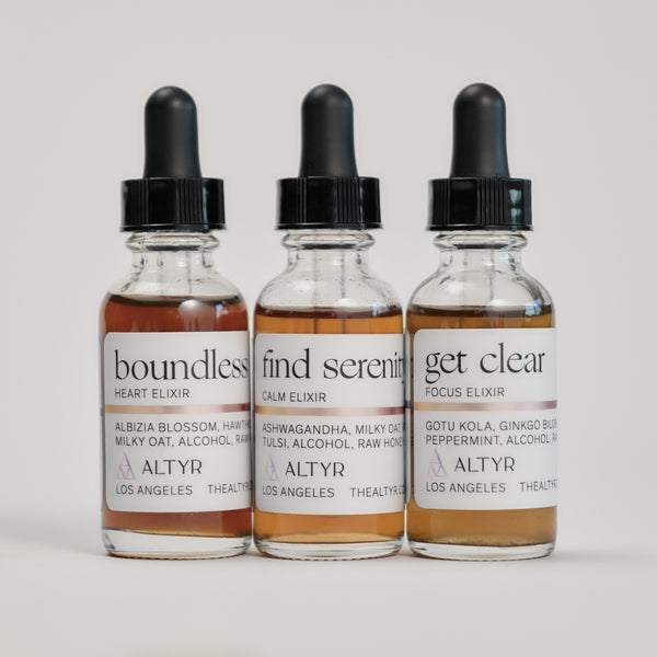 Tincture Bundle consisting of Boundless Love Heart Elixir, Find Serenity Calm Elixir, and Get Clear Focus Elixir on a white floor