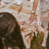 Six women celebrating an upcoming marriage with team bride stickers on their hands and flower bracelets on their wrists