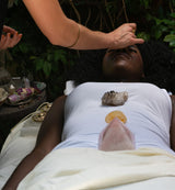 a woman lying down going through a personalized journey with a practitioner using crystals on her body