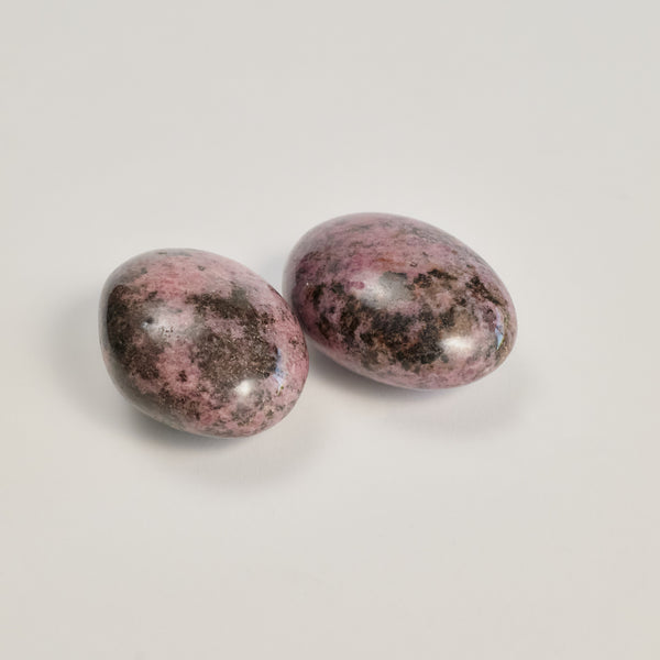 Two Rhodonite stones on a white floor