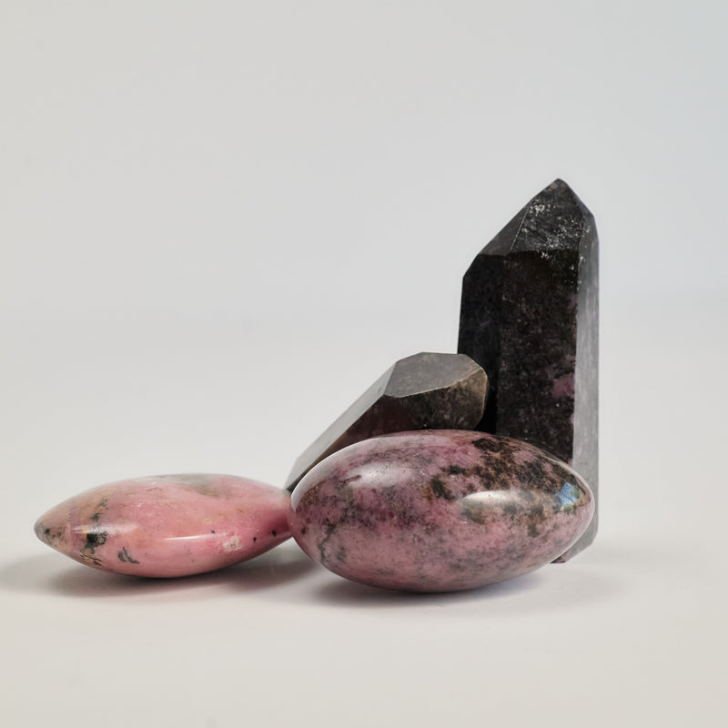 A couple of Rhodonite stones on a white floor