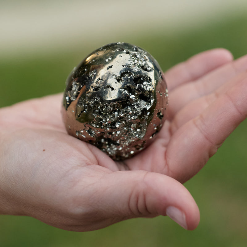 A person holding a Pyrite stone on her hand