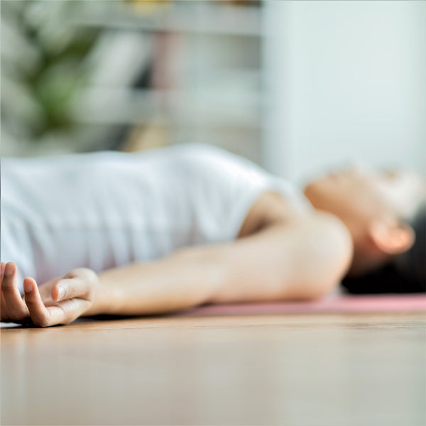 A blurry image with a woman laying down on a yoga mat