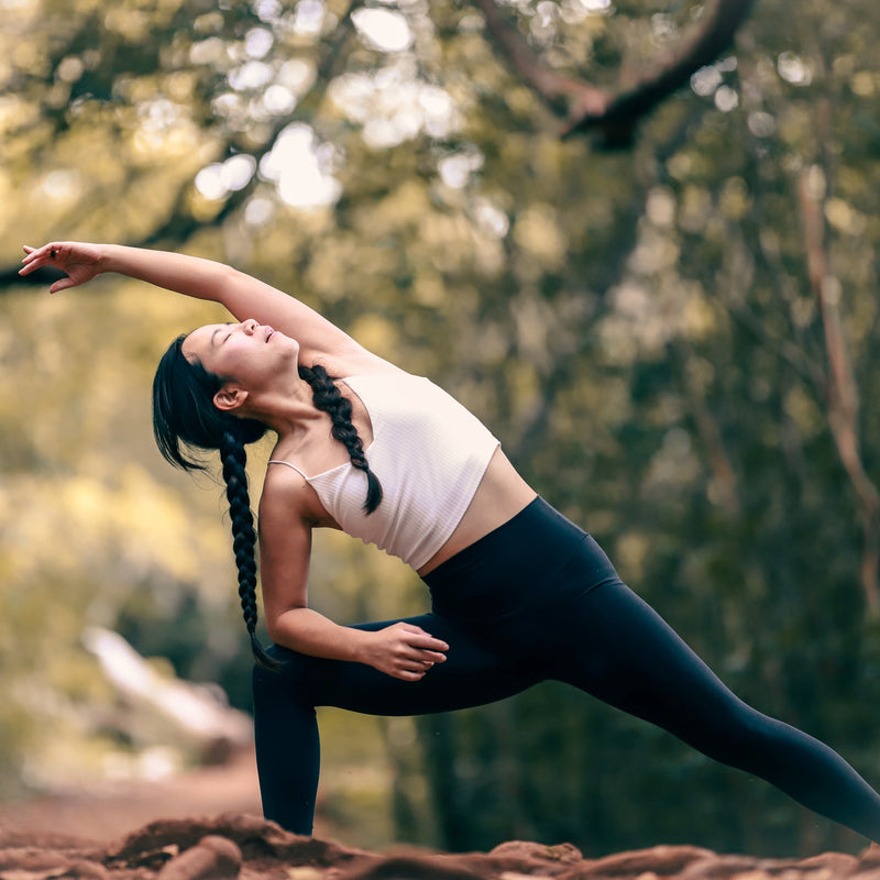 A woman doing yoga in nature with a blurry background